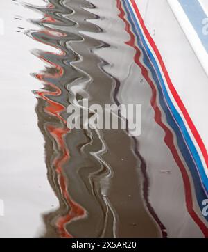 Wroxham, Norfolk, England, April, 2024 colourful lines of paint on a boat are reflected in ripples in the water Stock Photo