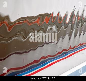 Wroxham, Norfolk, England, April, 2024 colourful lines of paint on a boat are reflected in ripples in the water Stock Photo