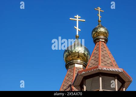 The church building features two gold crosses on the steeple, reaching up into the sky as a prominent finial atop the roof Stock Photo