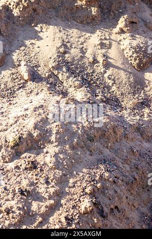 A mixture of soil, brown bedrock, and small rocks resembling a mini landscape. The pattern of rocks creates an interesting contrast in the grassy area Stock Photo