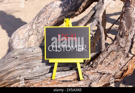 Ideal customer symbol. Concept words Ideal customer on beautiful black yellow blackboard. Beautiful tree background. Business ideal customer concept. Stock Photo