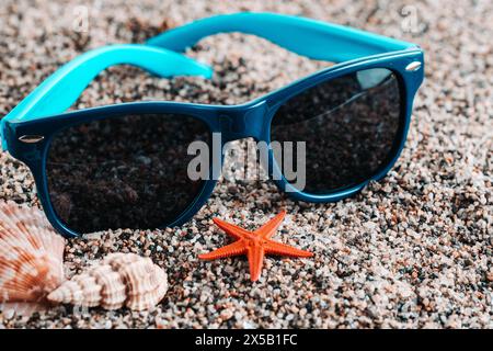 Sunglasses with starfish and seashells on sandy beach Stock Photo