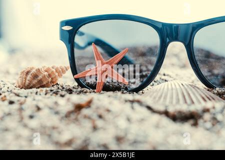 Sunglasses and starfish on sand with seashells. Travel concept Stock Photo