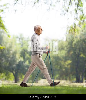 Full length profile shot of a mature man with walking poles in a park Stock Photo