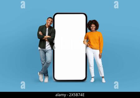 Two African American People Standing Next to A Big Phone Stock Photo