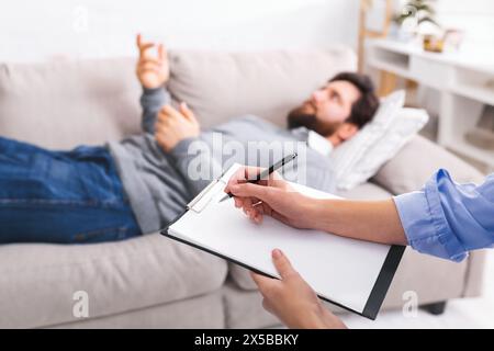 Therapist Taking Notes While Man Discusses Issues During Counseling Session Stock Photo