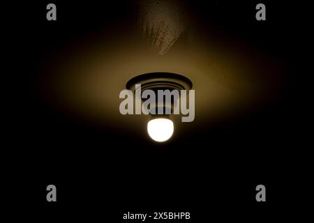 Hanging lightbulbs connected by a cable on the wall. Close-up light decoration with in a dark room. Stock Photo