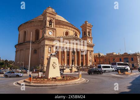 Mosta, Malta - August 25, 2019: Rotunda of Mosta. Exterior of Sanctuary Basilica of the Assumption of Our Lady. Street view with people and cars on th Stock Photo