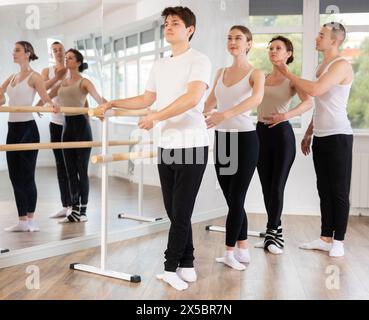 Ballet students practicing basic positions at barre with instructor Stock Photo