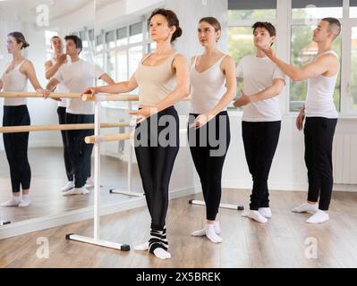 Ballet students practicing basic positions at barre with instructor Stock Photo