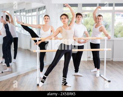 Group of people doing ballet exercises and posing using barre in gym in health and fitness concept Stock Photo