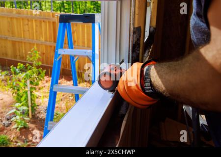 New house construction worker installing plastic windows with screwdriver Stock Photo