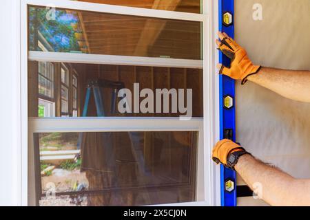 During construction of new home, construction worker installs plastic windows Stock Photo