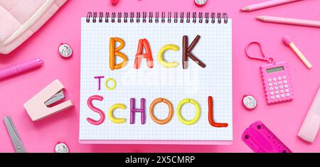 Stationery and notebook with text BACK TO SCHOOL on pink background Stock Photo