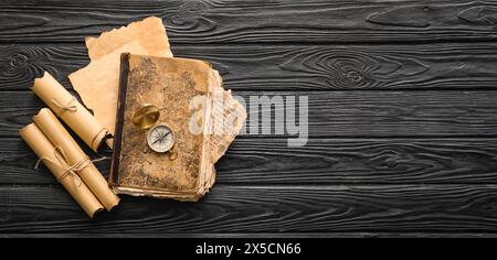 Old book with compass and scrolls on dark wooden background with space for text Stock Photo