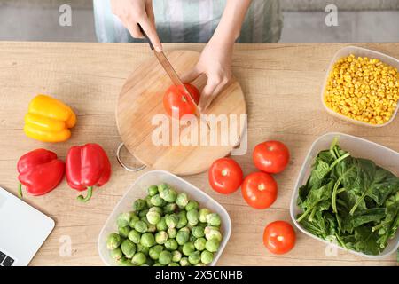 Woman cutting fresh tomatoes for freezing on wooden table Stock Photo
