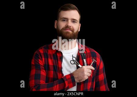 Young bearded man with scissors and razor on dark background Stock Photo
