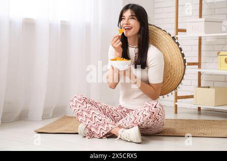 Young woman with sombrero and nachos at home. Cinco de Mayo celebration Stock Photo