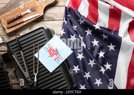 Greeting card for Independence Day, USA flag and barbecue utensils on wooden table, closeup Stock Photo