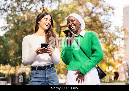female friends laughing using their mobile phones Stock Photo