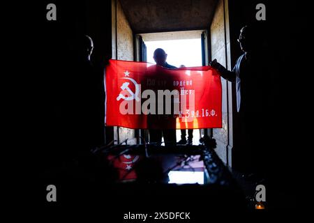 Berlin, Germany. 09th May, 2024. Visitors hold a flag showing the sickle and hammer at the Soviet memorial in Treptower Park. May 8 and 9 marks the 79th anniversary of the liberation from National Socialism. Credit: Christoph Soeder/dpa/Alamy Live News Stock Photo