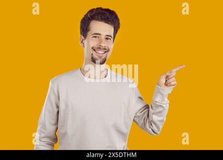 Cheerful young man pointing his finger to empty space Stock Photo