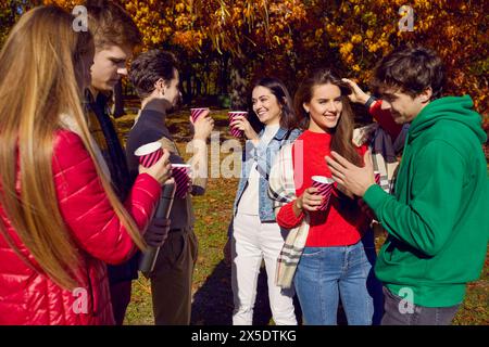 Happy friends having fun standing together with drinks in park Stock Photo