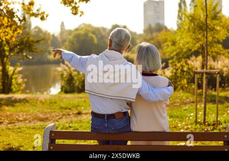Romantic senior couple in love on date talking while sitting on park bench. Stock Photo