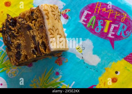 slice of Easter Simnel Cake on Happy Easter serviette napkin - all butter delicately spiced fruit cake with a layer of soft marzipan Stock Photo