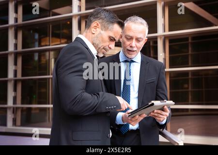Two businessmen with digital tablet looking at the results of the project. Stock Photo