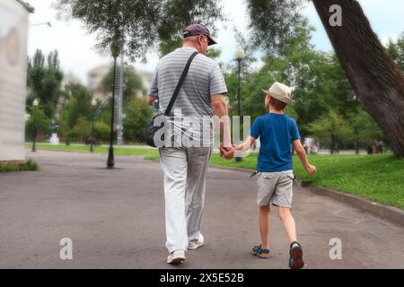 Father and his 7 year old son are walking in park and talking. Back view. Father's Day. Stock Photo