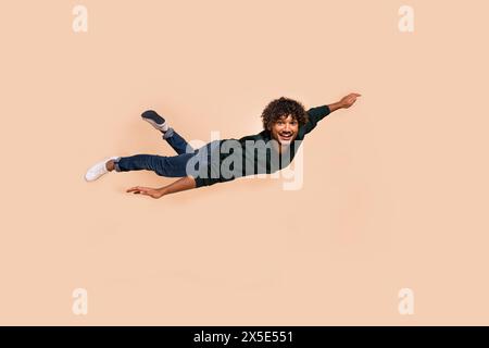 Full size photo of nice young man flying wear sweater isolated on beige color background Stock Photo