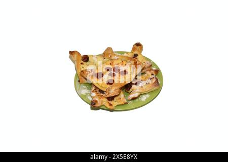 On a green plate, which stands on a white background, there are cookies baked from puff pastry. Stock Photo
