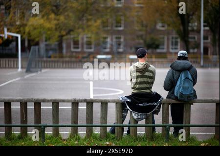 Two Young man on a Railing Two Young Adult Males having a Personal Conversation sitting down on a Soccer Field s Fence, Rotterdam, Netherlands. Rotterdam Zuid-Holland Nederland Copyright: xGuidoxKoppesxPhotox Stock Photo