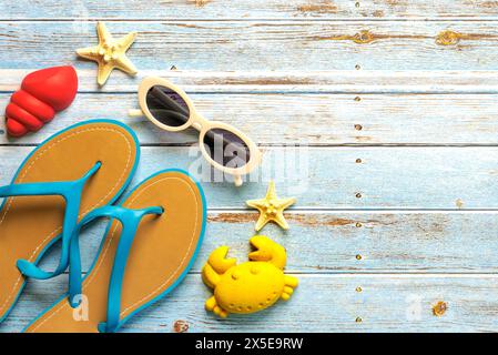 Top view of flip flops,sunglasses, starfish and beach toys with copy space for text on a background of wooden boards. Summer holiday concept Stock Photo