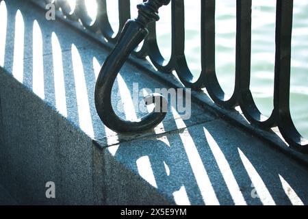High contrast silhouette of wrought iron black fence on a concrete parapet on a shore. Patterns and textures of architectural details. Metal structure Stock Photo