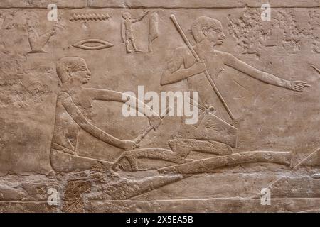 Egyptian bas-relief sculpture showing two men rowing out to fish for food. Pyramid of Unas, in the Necropolis of Saqqara, Egypt. Stock Photo