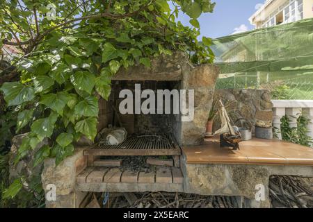 A barbecue built with stone and cement with metal rods and vines on it Stock Photo