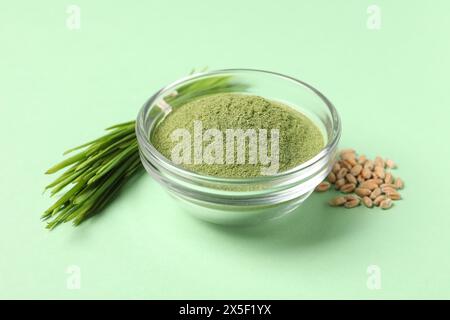 Wheat grass powder in bowl, seeds and fresh sprouts on green table Stock Photo