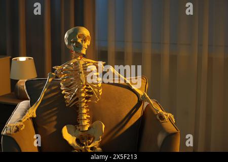 Waiting concept. Human skeleton sitting in armchair indoors Stock Photo