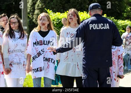 Ukrainian women painted in red protest as Russian ambassador to Poland comes to lay flowers at the Mausoleum of the Soviet Soldiers Cemetery on Russian Victory Day, May 9, 2024 in Warsaw, Poland. High security was present with the Russian Ambassador. Ukrainian protesters demonstrated as the Russian ambassador arrived. Stock Photo