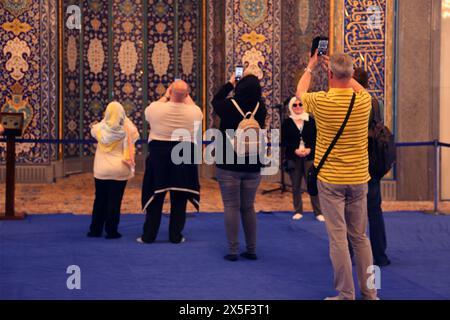 Sultan Qaboos Grand Mosque Interior Tourists Standing on the Protective Blue Carpet by the Mihrab Taking Photographs on Smartphones Muscat Oman Stock Photo