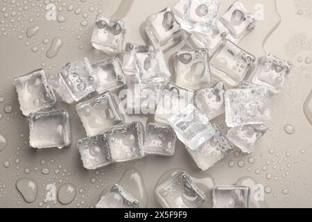 Melting ice cubes and water drops on light grey background, flat lay Stock Photo