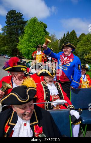 Town criers smile (bellmen & bellwomen in colourful braided crier's livery uniforms) sitting on open-top bus deck - Ilkley, West Yorkshire England UK. Stock Photo