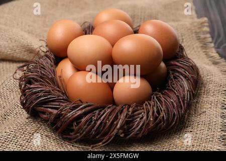 Fresh chicken eggs in nest on burlap fabric, closeup Stock Photo