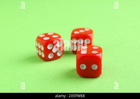 Three red game dices on green background, closeup Stock Photo