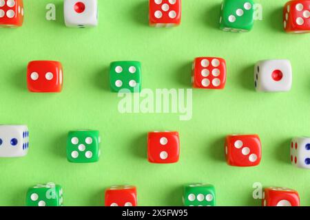 Many color game dices on green background, flat lay Stock Photo