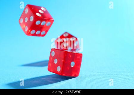 Three red game dices falling on light blue background, closeup. Space for text Stock Photo