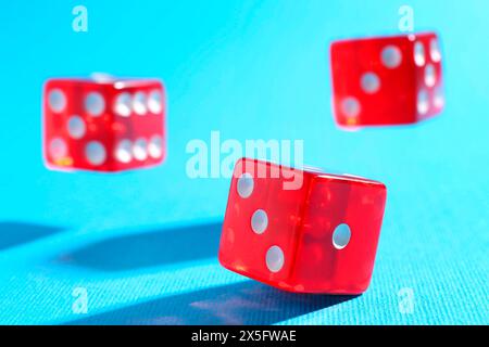 Three red game dices falling on light blue background, closeup Stock Photo