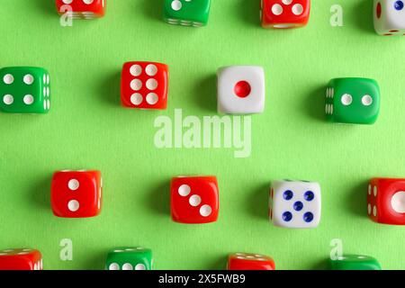 Many color game dices on green background, flat lay Stock Photo